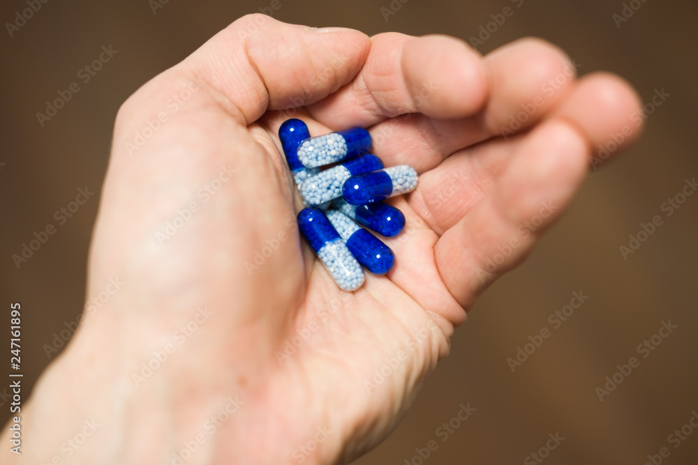 holding blue pills in a hand holding blue pills in a hand
