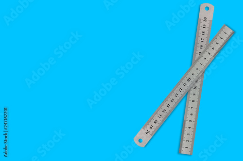 Pair of metal straightedges with digits and scale on blue background with copy space for your text