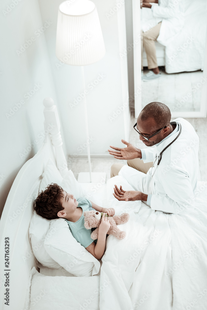 Fototapeta premium Pleased brunette boy listening to his doctor