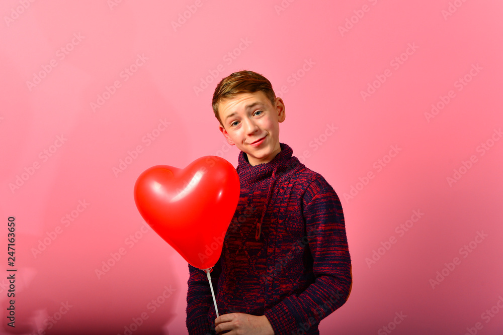 A boy among the red heart balloons in the form of a heart on a pink background for Valentine's Day and March 8th. A boy among the red heart balloons in the form of a heart on a pink background for Valentine's Day and March 8th.