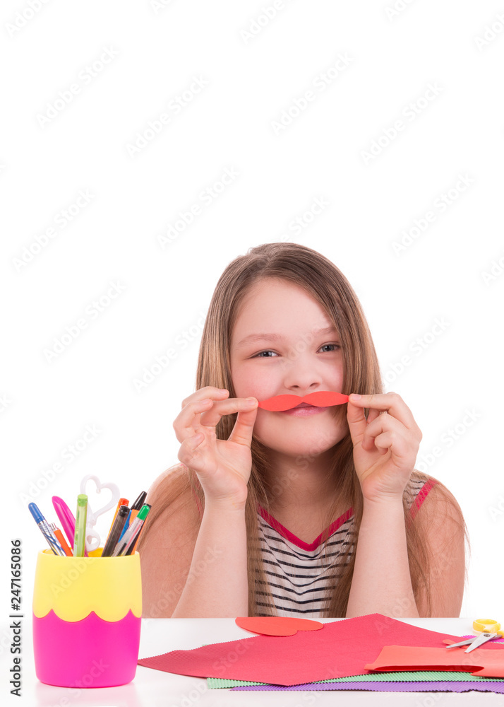 Teen girl cuts paper mustache. Teen girl cuts out of colored paper on a white background. Teen girl cuts paper mustache. Teen girl cuts out of colored paper on a white background.