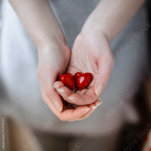 Young woman holding in hands two red hearts on gray background.Valentine Day concept.