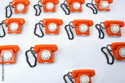 Close up of a large group of orange rotary telephones