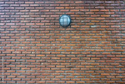 Street lamp hanging on the dirty brick wall background.