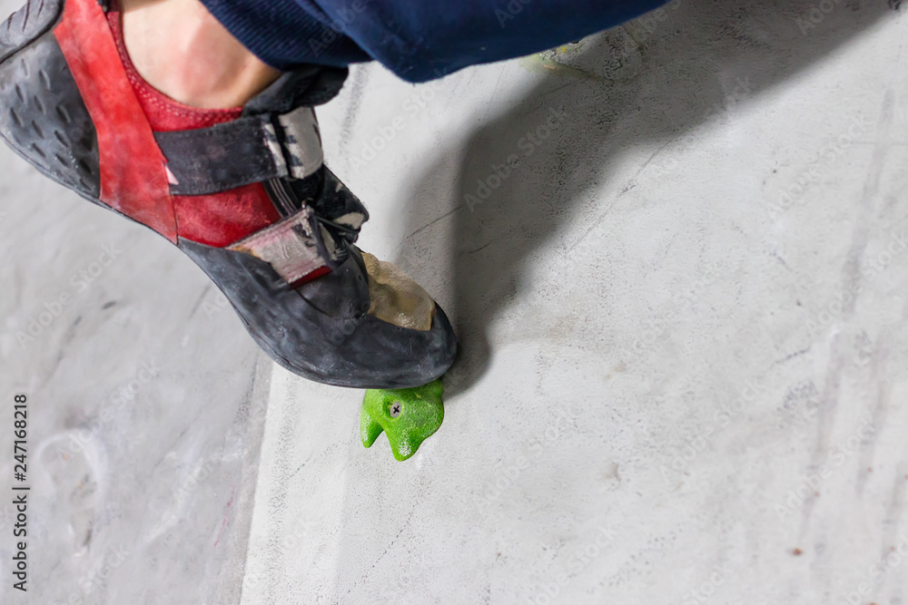rocky shoe on a tiny, scanty snare stands with the tip of the sock in close-up on the climbing wall in the room rocky shoe on a tiny, scanty snare stands with the tip of the sock in close-up on the climbing wall in the room