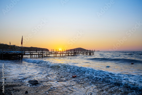 Wooden pier bridge in the blue sea in afternoon sunset