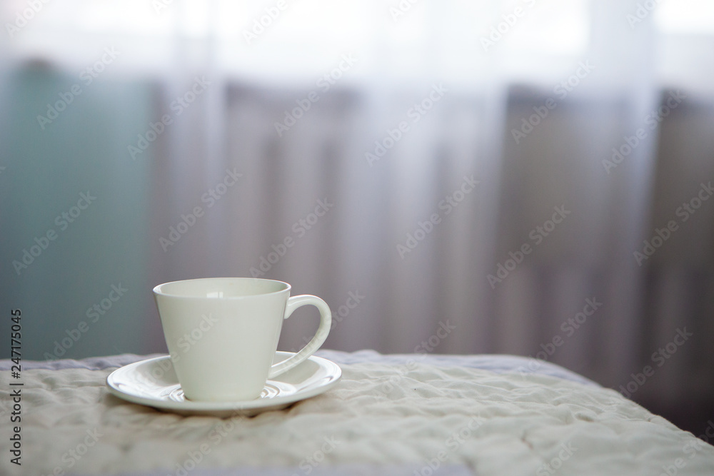 morning cup of coffee on the background of the bed and the window