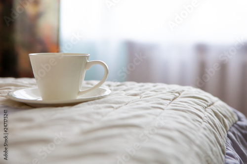 morning cup of coffee on the background of the bed and the window