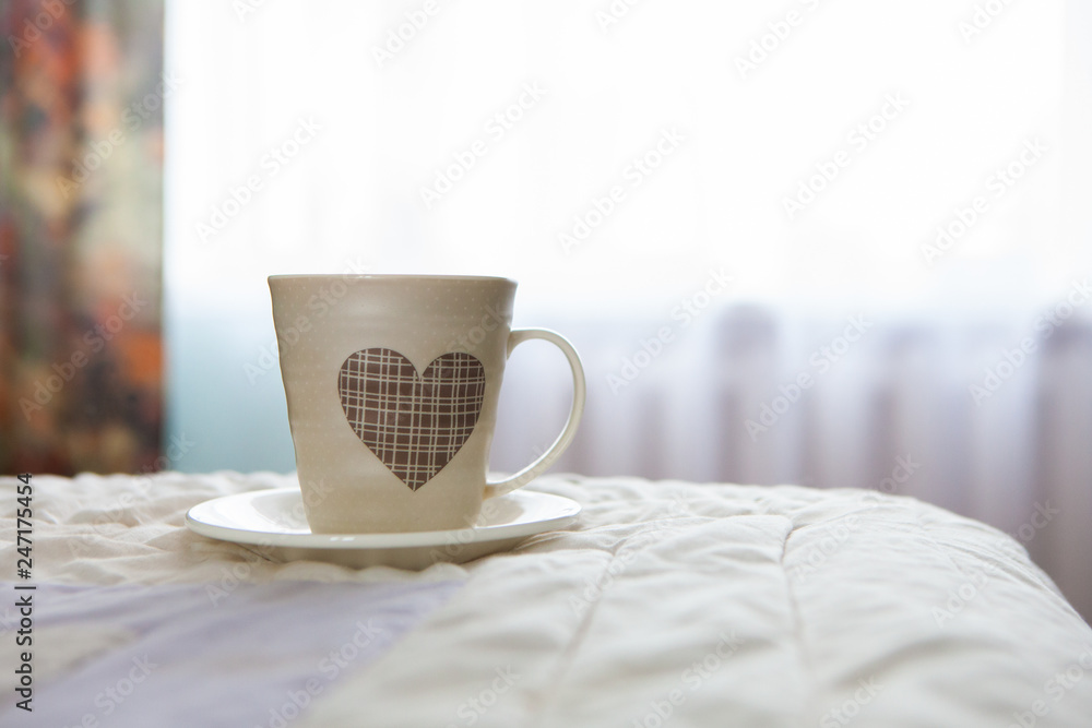 morning cup of coffee on the background of the bed and the window