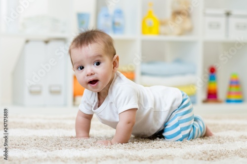 funny baby boy crawling on floor in nursery or at home