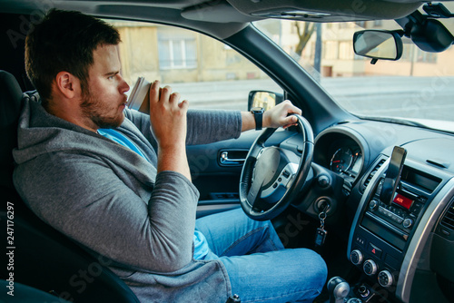 man driving car and drinking coffee