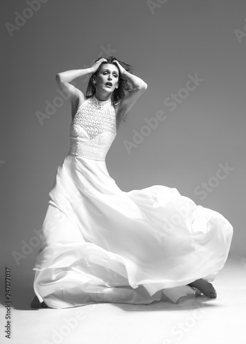 woman dancing classic dance in white dress on gray background. Emotionally and Dramatically