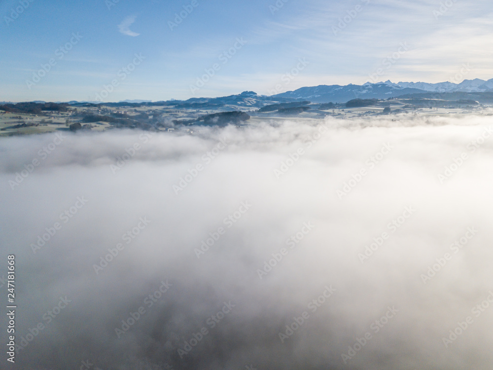 Obraz premium Aerial view of rural landscape in Switzerland covered with fog. Cold morning in winter with beautiful light.