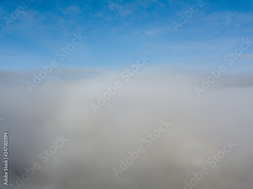 Aerial view of rural landscape in Switzerland covered with fog. Cold morning in winter with beautiful light. View from above the clouds with impressive sunlight. © Mario