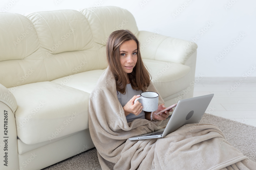 Working, cozy, people concept - young woman working at home in plaid, drinking tea and chatting in netbook Working, cozy, people concept - young woman working at home in plaid, drinking tea and chatting in netbook
