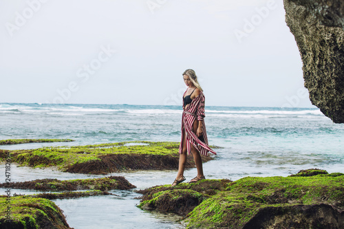 Woman portrait in a tunic and bikini on a beautiful reef beach among the rocks sensual and emotional