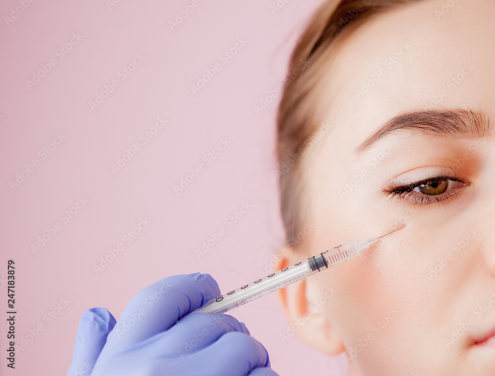 The doctor cosmetologist makes the Botulinotoxin injection procedure for tightening and smoothing wrinkles on the face skin of a beautiful, young woman in a beauty salon.Cosmetology skin care The doctor cosmetologist makes the Botulinotoxin injection procedure for tightening and smoothing wrinkles on the face skin of a beautiful, young woman in a beauty salon.Cosmetology skin care