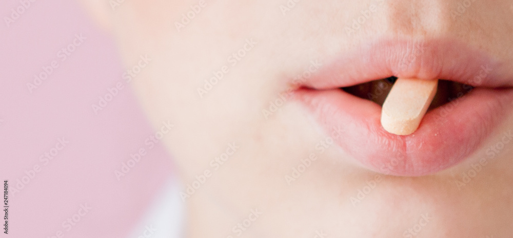 Obraz premium pink tablet in the mouth of the woman, close-up face