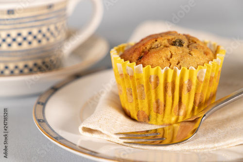 Banana chocolate chip muffin on side plate, light blue background, with shallow depth of field. photo