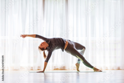 Caucasian woman is practicing yoga at studio