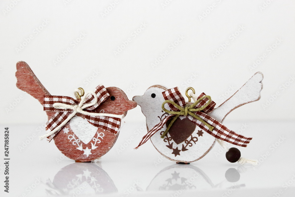 Fototapeta premium Valentine's day concept. Couple in love, just married or honeymoon concept. Couple of wooden birds looking at each other with painted hearts and fabric bows with reflection.