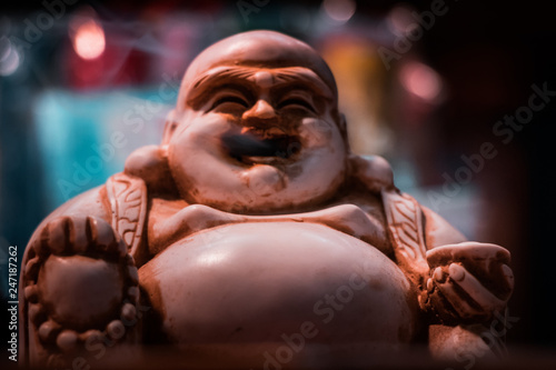 Front view of the iconic Smoking Buddha. Macro shot close up of smoke floating out of the mouth. Incense stick holder  Indian religious symbol  yoga and meditation concept.