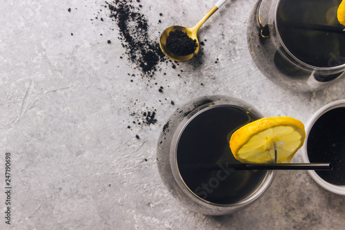 Black lemonade with charcoal and lemon on a light background