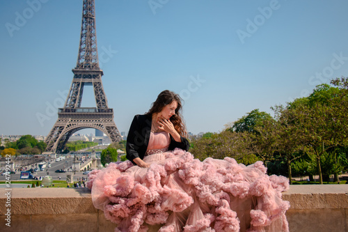 Beautiful hipster girl dressed to impress in a pastel pink ballroom dress with Eiffel Tower in background
