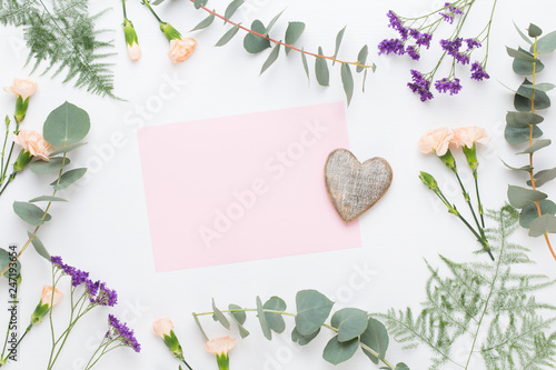 Flowers composition. Paper blank, carnation flowers, eucalyptus branches on pastel  background. Flat lay, top view, copy spaceFlat lay stiil life. photo