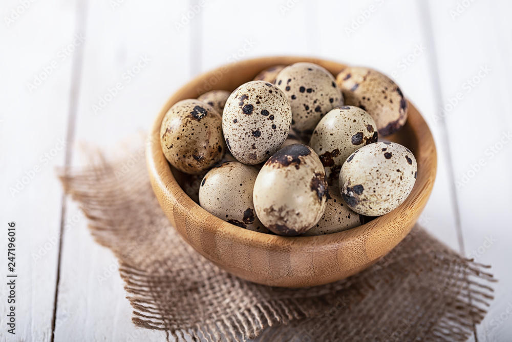 Obraz premium quail eggs in wooden plate over white background