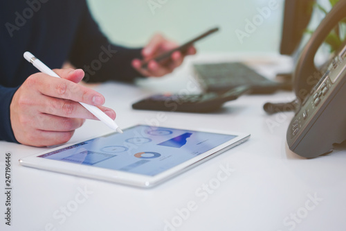 close up trader man hand on tablet with stock graph dashboard and holding smartphone for check news at desk , multitasking people concept 