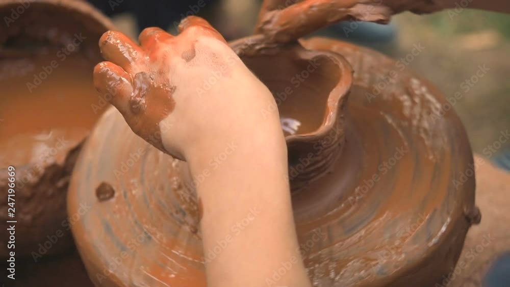 Rotating potter's wheel and clay ware on it taken from above. A child sculpts his hands with a clay cup on a potter's wheel. Hands in clay. Pottery male ceramist creates a hand made clay product Rotating potter's wheel and clay ware on it taken from above. A child sculpts his hands with a clay cup on a potter's wheel. Hands in clay. Pottery male ceramist creates a hand made clay product