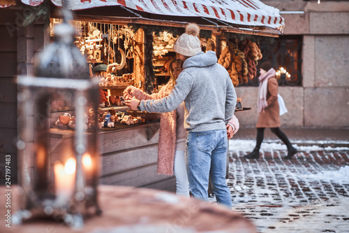 A happy young couple choosing the gift in a souvenir shop outdoors on a winter fair at a Christmas time.