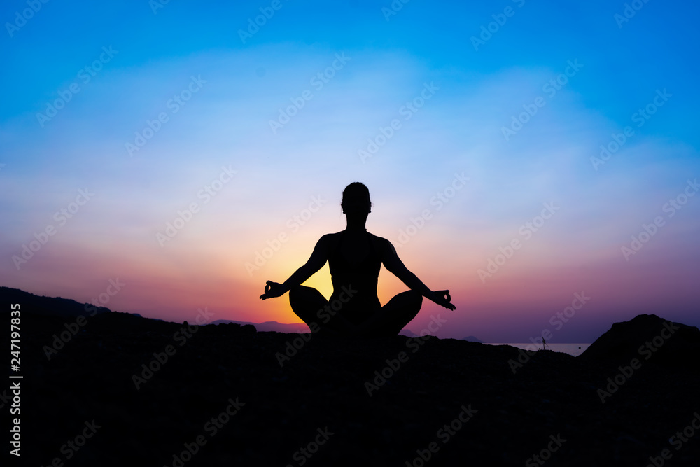 Silhouette of a young woman doing yoga on the beach at sunset. Silhouette of a young woman doing yoga on the beach at sunset.