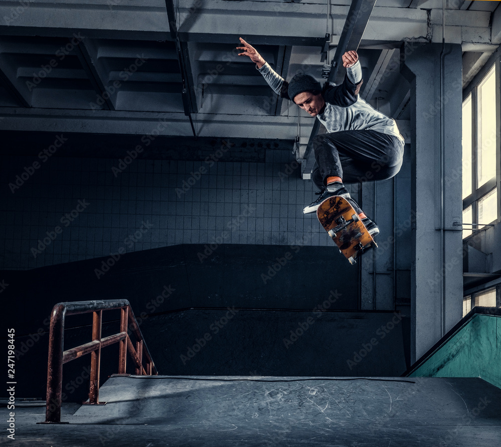 Skateboarder jumping high on mini ramp at skate park indoor. - obrazy, fototapety, plakaty 