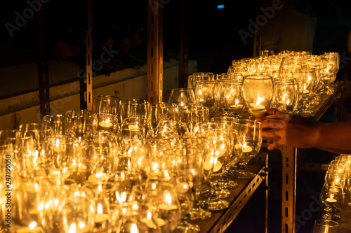 Hand of a man holding burning candel in glass for praying in temple Buddism