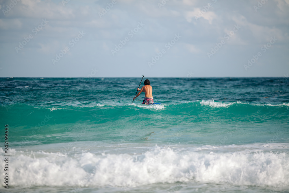 Man sails surfing on the waves in the Caribbean, in Cancun, Mexico