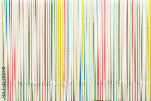 Striped colored plastic cocktail straws as background