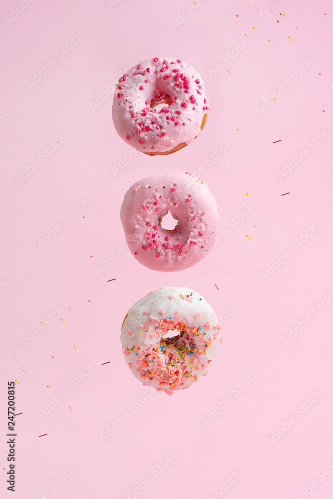 Sprinkle pink donuts. Frosted sprinkle donut on a pink background. Three tasty and sweet donuts