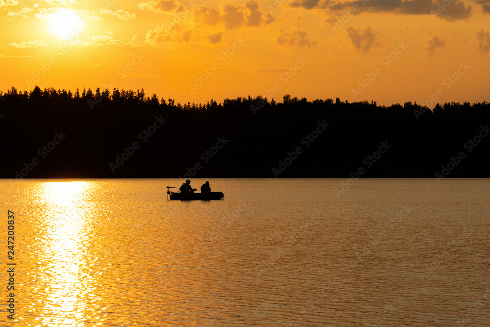 Fishermen catch fish on the lake at sunset.