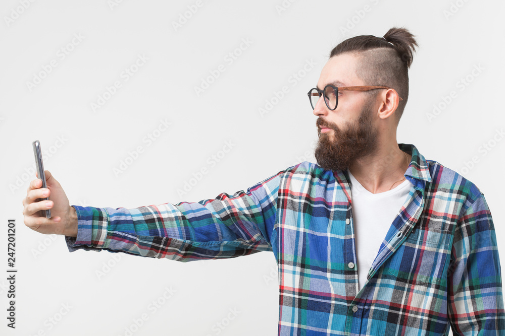 Hipster, people concept - Young hipster with beard in glasses taking selfie