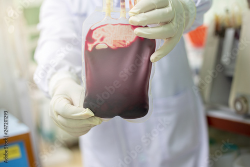 The doctor holds a blood bag for the patient.