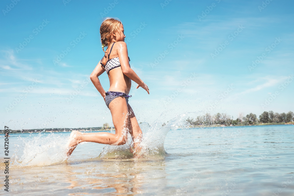 Naklejka premium Little girl run in river water. Summer days fun time