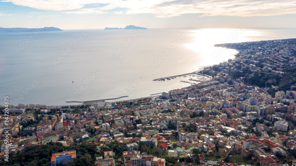 Aerial view at the dusk of the waterfront of Naples, the Chiaia and Mergellina neighborhoods, from the Vomero hill. There are on background Capri Island, Posillipo and Fuorigrotta districts.