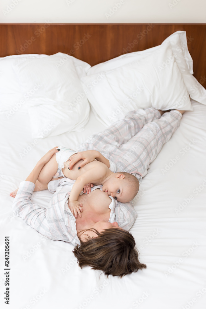 Young mother laying down with her baby boy and breast feeding Young mother laying down with her baby boy and breast feeding