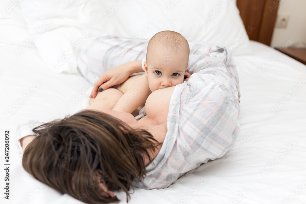 Young mother laying down with her baby boy and breast feeding Young mother laying down with her baby boy and breast feeding