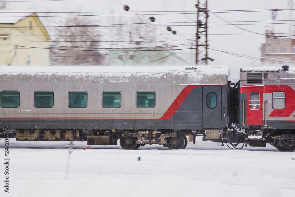 Fototapeta premium passenger train travels fast along a snowy railroad