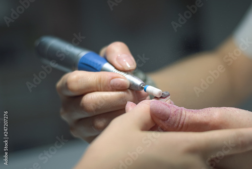 Manicurist master is removing an old nail varnish by hardware manicure. Nail care concept.