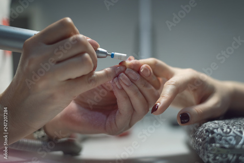 Manicurist master is removing an old nail varnish by hardware manicure. Nail care concept.