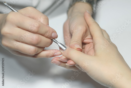 Manicurist is using a nail scraper on the female fingernails. Nail care concept.